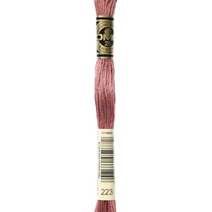 May include: A spool of DMC embroidery floss in color 223, a muted rose pink. The spool is labeled with the DMC logo and the number 223.