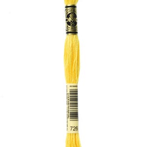 Puede incluir: Una bobina de hilo de bordar DMC en color 726, un amarillo brillante. La bobina está etiquetada con el logotipo de DMC y el número de color.