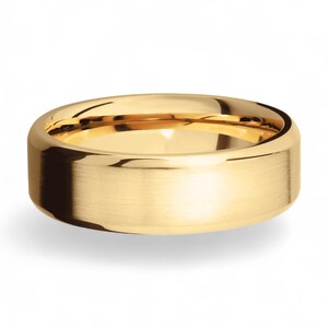 Op de afbeelding: Een goudkleurige ring met een geborstelde afwerking. De ring heeft een platte, brede band en een afgeronde binnenkant. De ring is waarschijnlijk gemaakt van goud en is ontworpen voor dagelijks gebruik.