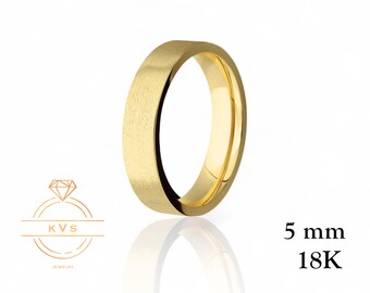 May include: A gold-colored ring with a brushed finish. The ring is 5 mm wide and made of 18K gold. The ring is displayed on a white background with a reflection. The image also includes a logo and text.