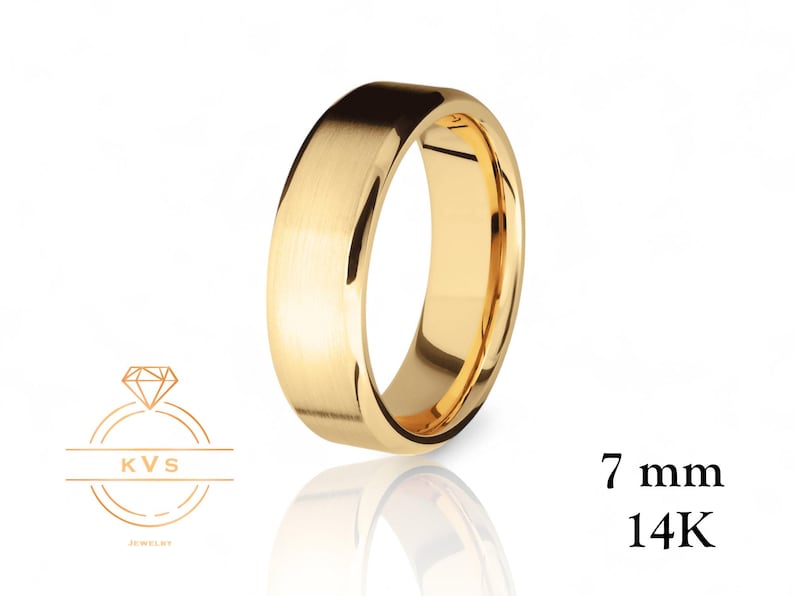 Op de afbeelding: Een goudkleurige ring met een geborstelde afwerking, 7 mm breed, gemaakt van 14K goud. De ring wordt getoond tegen een witte achtergrond met een reflectie. Het KVS Jewelry logo staat linksonder.