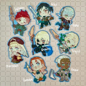 May include: A collection of nine chibi-style stickers featuring characters from the video game Fire Emblem: Three Houses. Each sticker has a blue outline and depicts a different character, including Sylvain, Felix, Ashe, Mercedes, Dimitri, Ingrid, Annette, and Dedue.