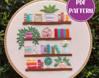 May include: Embroidered pattern for a bookshelf with plants, books, and a globe. The pattern includes a variety of colors, including green, blue, red, and yellow. The pattern is perfect for a beginner embroiderer.