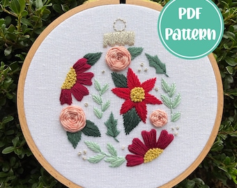 Peut inclure: Un cercle de broderie blanc avec un motif floral de fleurs rouges, roses et vertes. Le motif est en forme de boule de Noël. Le texte "PDF Pattern" est dans un cercle turquoise sur le côté droit de l'image.