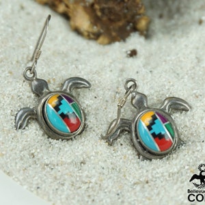May include: Sterling silver earrings featuring a turtle design with inlaid turquoise, red, yellow, green, purple, and black stones.