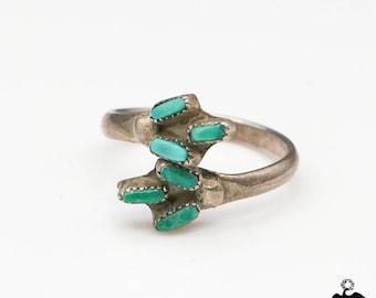 May include: A silver ring with turquoise stones set in a unique design. The ring is made of sterling silver and features a cluster of turquoise stones in a geometric pattern.
