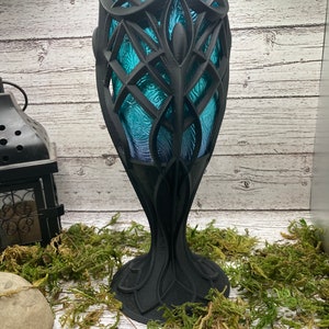 Könnte beinhalten: Ein schwarzer, 3D-gedruckter Kelch mit einem blauen Glaseinsatz. Der Kelch hat ein dekoratives, filigranes Design und eine breite Basis.