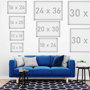 May include: A white wall displays various framed art sizes, including 11 x 17 inches, 16 x 24 inches, and 30 x 45 inches. A blue sofa with pillows and a black side table with decor are in front of a patterned rug.