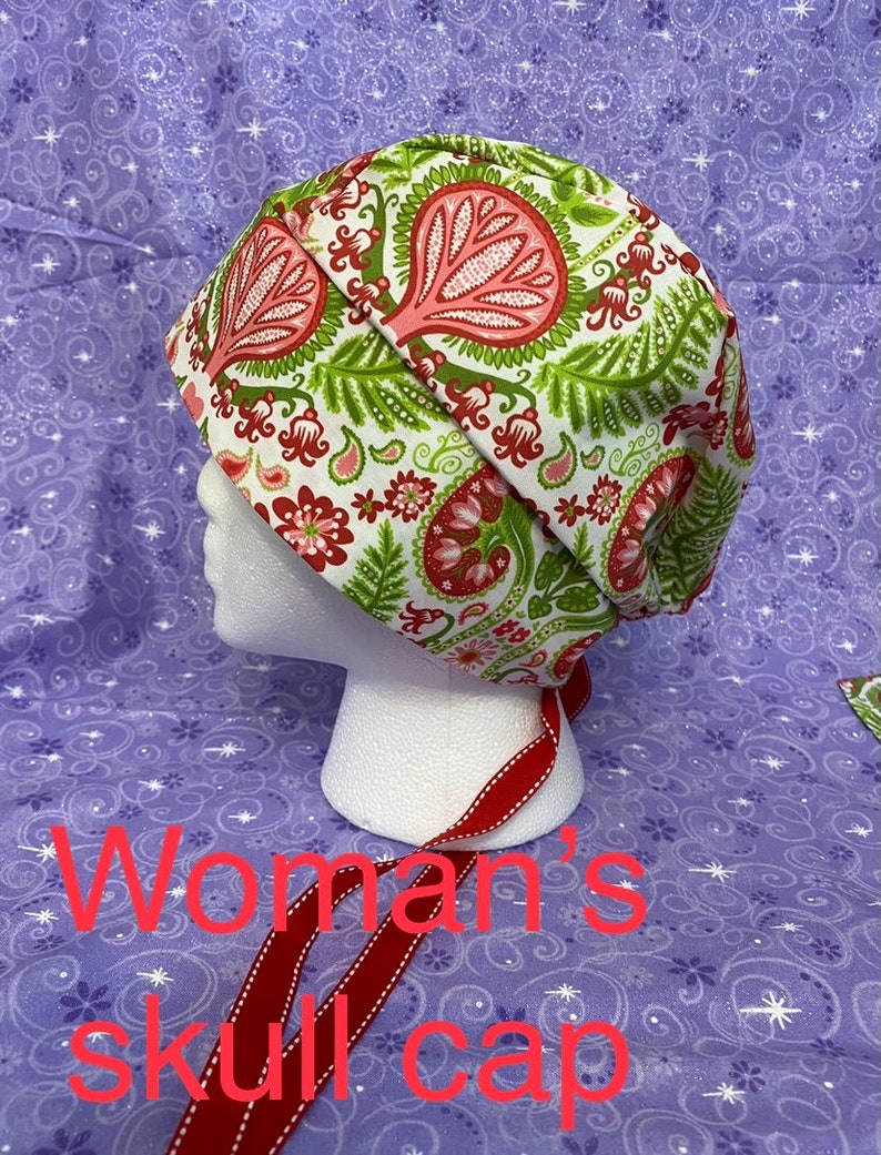 May include: A white skull cap with a red, green, and pink paisley pattern. The cap has a red ribbon tie.