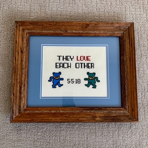 May include: Framed cross-stitch with the text "They love each other" and two dancing bears, one blue and one green. The date "5-5-18" is stitched below the bears.