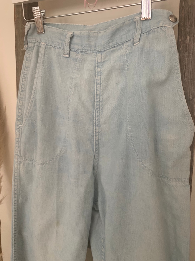 May include: Light blue high-waisted denim pants with a straight leg and multiple pockets.