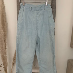 May include: Light blue denim pants with a high waist and two large pockets on the front. The pants are cropped and have a relaxed fit.