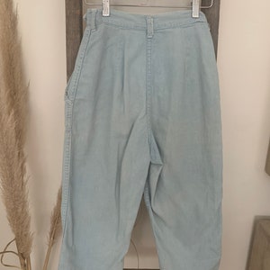 May include: Light blue denim pants with a high waist and a straight leg. The pants have a button fly and belt loops.
