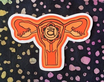 May include: Orange and white sticker of a uterus with a stylized orange and white symbol of the sacral chakra, the second chakra, with the Sanskrit symbol "Svadhisthana" inside.