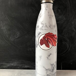 May include: White marble water bottle with a red and pink fish sticker on the side.
