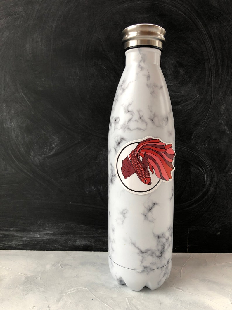 May include: White marble water bottle with a red and pink fish sticker on the side.