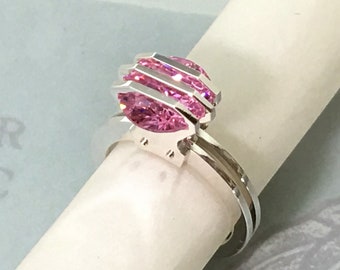 May include: A silver ring with a pink marquise-shaped gemstone set in a geometric design.