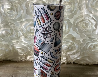 Könnte beinhalten: Ein weißer Edelstahlbecher mit einem farbenfrohen Design zum Thema Wissenschaft. Der Becher zeigt Illustrationen von Bechergläsern, Reagenzgläsern, Atomen und anderen wissenschaftlichen Objekten. Er wird mit einem Edelstahlstrohhalm geliefert.