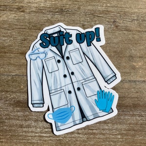May include: White lab coat sticker with the text "Suit up!" in blue. The sticker also includes illustrations of safety glasses, blue gloves, and a blue face mask.