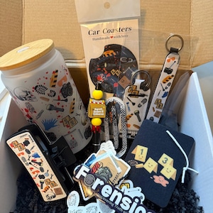 May include: An open cardboard box filled with forensic-themed items. Includes a tumbler, car coasters, keychains, stickers, and a tag. The items feature crime scene elements, footprints, and the word "Forensics".
