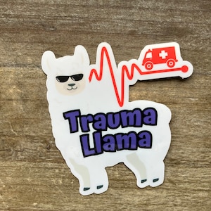 May include: A white sticker featuring a cartoon llama wearing sunglasses. The text "Trauma Llama" is in purple and black. A red heartbeat line and ambulance graphic are also included.