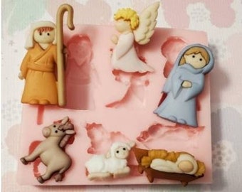 May include: A silicone mold for making Christmas-themed cake decorations. The mold features a shepherd, an angel, a donkey, a lamb, a manger, and a baby Jesus.