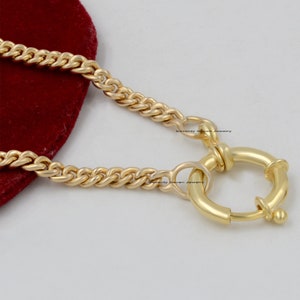 Könnte beinhalten: Goldkette mit rundem Verschluss. Die Kette ist im Curb-Stil mit einer strukturierten Oberfläche.