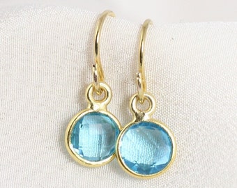 May include: A pair of gold dangle earrings with light blue oval-shaped gemstones.