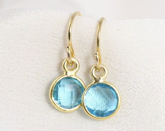 May include: A pair of gold dangle earrings with light blue oval-shaped gemstones.