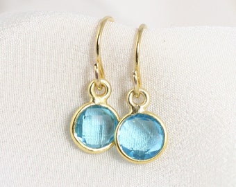 May include: A pair of gold dangle earrings with light blue oval-shaped gemstones.
