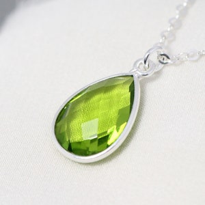 May include: A silver chain necklace with a pear-shaped green gemstone pendant.