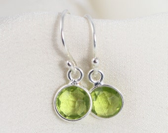 May include: A pair of silver dangle earrings with green oval-shaped gemstones.