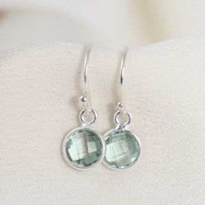 May include: A pair of silver dangle earrings with light green gemstone drops.