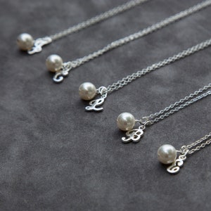 May include: Four silver necklaces with pearl charms and letter pendants. The letters are L, B, B, and B.