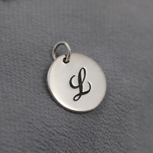 May include: A silver charm with a cursive letter L engraved on it.