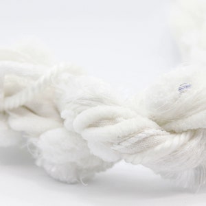 Peut inclure: Gros plan sur une corde blanche épaisse avec un design torsadé. La corde a une surface texturée et est composée de plusieurs brins. L'image est sur fond blanc, soulignant les détails de la corde.