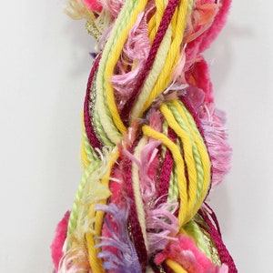 May include: A bundle of colorful yarn with pink, yellow, green, and burgundy strands. The yarn is fluffy and has a textured look.