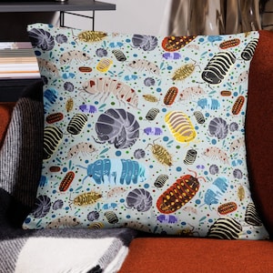 May include: A blue and white throw pillow with a repeating pattern of colorful pill bugs. The pill bugs are in various poses and colors, including red, yellow, blue, and black.