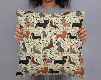 May include: A cream-colored throw pillow with a repeating pattern of dachshund dogs in various colors and poses. The dogs are surrounded by green leaves and brown acorns.