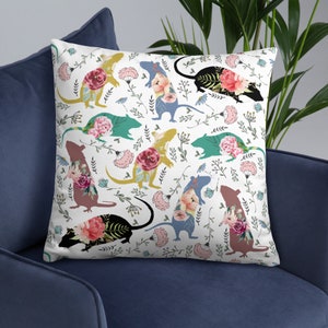 May include: A white cushion with a floral pattern featuring silhouettes of rats. The rats are outlined in black and filled with watercolour floral designs in shades of pink, blue, green, and yellow.