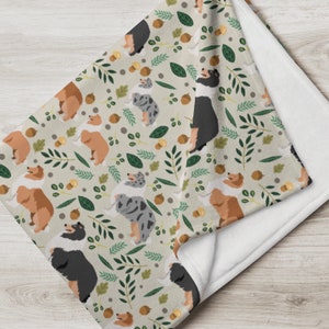 May include: A soft, plush throw blanket featuring a repeating pattern of colorful Collie dogs and autumn leaves on a beige background.