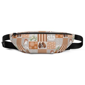 May include: A brown and tan fanny pack with a patchwork design featuring a repeating pattern of Cavalier King Charles Spaniels, crowns, paw prints, and floral accents. The text "Cavalia" is repeated throughout the design.