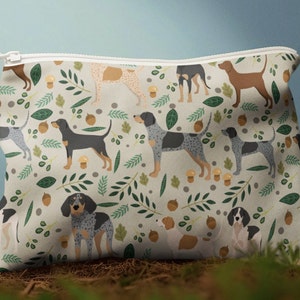 May include: A white zippered pouch with a repeating pattern of blue, black, and brown dogs with green leaves and brown acorns.