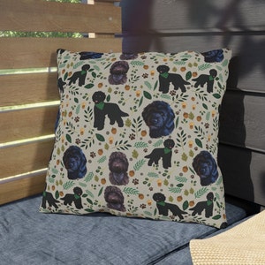 May include: A beige throw pillow with a repeating pattern of black dogs, green leaves, and brown acorns. The dogs are wearing green collars.