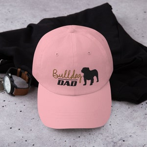 May include: Pink baseball cap with an embroidered black bulldog silhouette and the text "Bulldog DAD" in brown.
