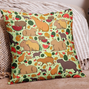 May include: A green pillow with a repeating pattern of capybaras, watermelons, oranges, and green leaves. The capybaras are brown and tan and are in various poses.