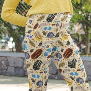 May include: A pair of beige leggings with a colourful pattern of various insects, including roly-polies, beetles, and other bugs.