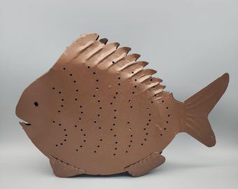 Portavelas grande de metal con forma de pez, color cobre.