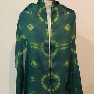 May include: A rectangular scarf featuring a deep teal base color with a repeating pattern of circular lime green tie-dye motifs. The fabric appears lightweight and semi-sheer, with the circular designs arranged in a symmetrical grid-like layout.