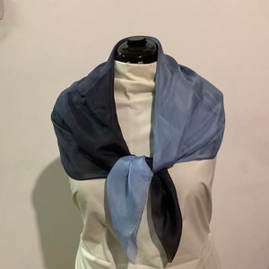 May include: A blue and black silk scarf tied around a mannequin's neck. The scarf is a gradient of blue and black.